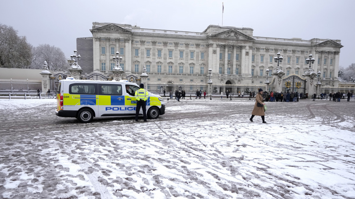 Őrködő rendőrök és turisták a londoni királyi rezidencia, a Buckingham-palota előtt egy hóesés után, 2022. december 12-én. Nagy-Britannia több térségében fordult téliesre az idő havazással és fagypont alatti hőmérséklettel.