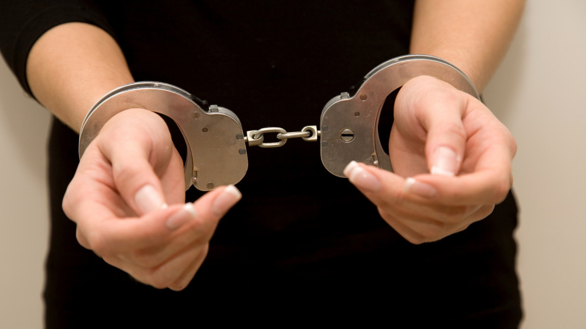 Female with manicured nails handcuffed.