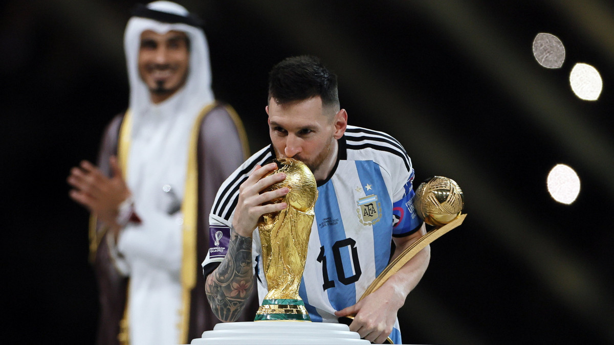 Az argentin Lionel Messi a legjobb játékosként elnyert díjjal megcsókolja a vb trófeáját, miután csapata 4-2-re győzött a katari labdarúgó-világbajnokság döntőjében játszott Argentína-Franciaország mérkőzés 3-3-as hosszabbítása utáni tizenegyes-párbajban a Loszaíl Stadionban 2022. december 18-án.