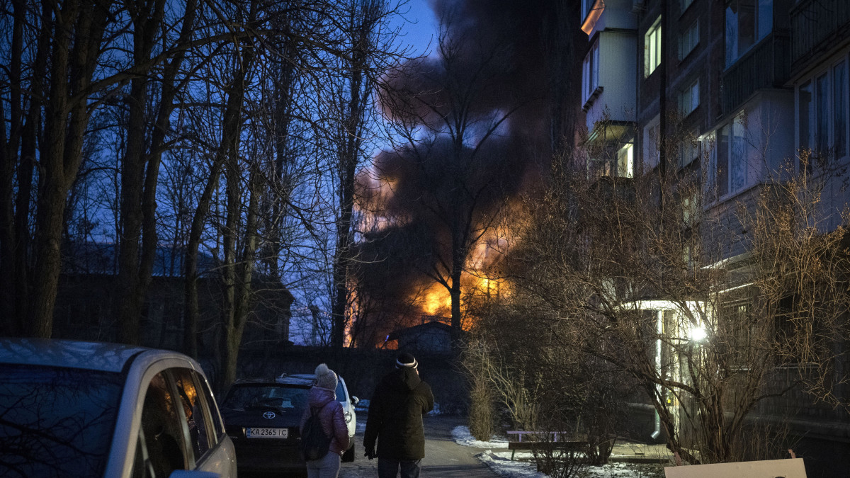 Orosz dróntámadás következtében kigyulladt épületet néznek emberek Kijevben 2022. december 19-én hajnalban. A kijevi hatóságok arról számoltak be, hogy több mint húsz iráni gyártmányú drónt észleltek a főváros légterében, melyek közül legalább 15-öt lelőttek. Egy fontos infrastrukturális létesítményt találat ért. Előzetes értesülések szerint a támadás nem követelt halottakat vagy sebesülteket.