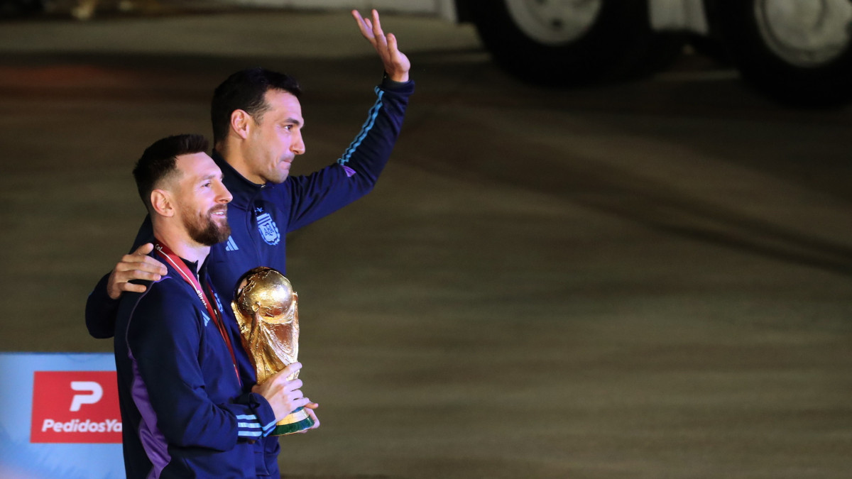 Lionel Messi argentin csapatkapitány (b) kezében a bajnoki trófeával és Lionel Scaloni szövetségi kapitány, miután a válogatott játékosaival megérkeztek a Buenos Aires-i Ezeiza repülőtérre 2022. december 20-án. Argentína két nappal korábban 4-2-re győzött a katari labdarúgó-világbajnokság döntőjében játszott Argentína-Franciaország mérkőzés 3-3-as hosszabbítása utáni tizenegyes-párbajban.
