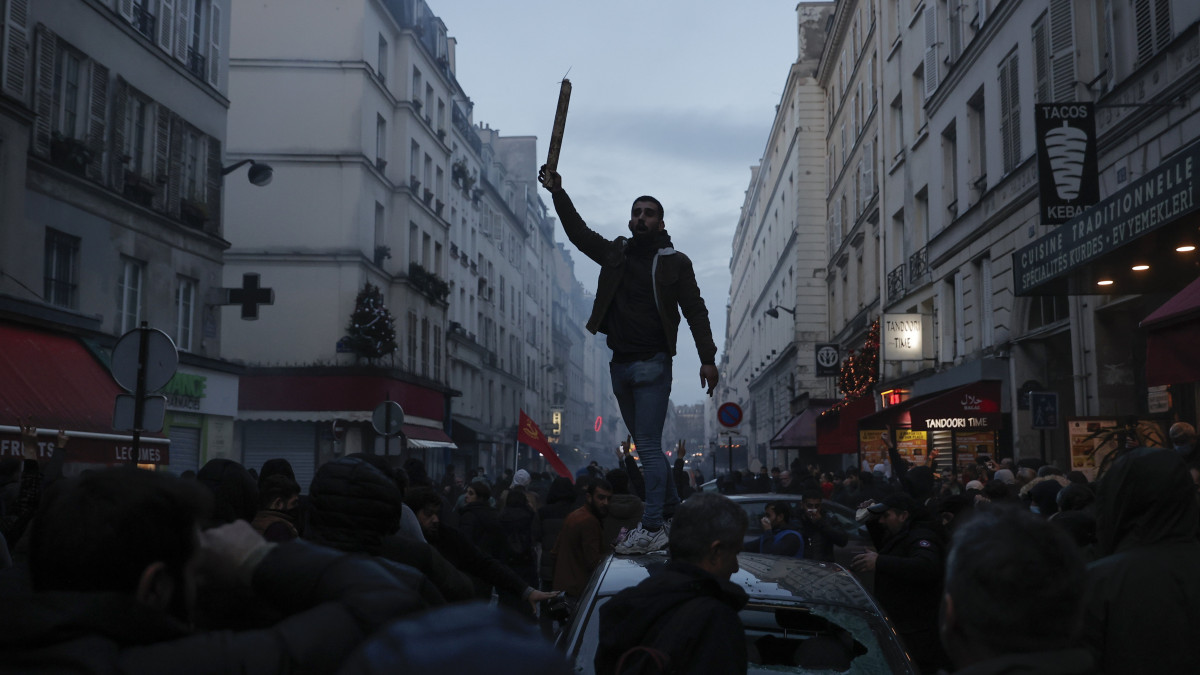 Kurd tüntető egy autó tetején, Párizsban 2022. december 23-án, miután néhány órával korábban egy férfi a közelben rálőtt többek között egy kurd kulturális központra, és legalább három embert megölt, hármat pedig megsebesített, kettőt életveszélyesen. A tüntetők a török kormányt kárhoztató jelmondatokat kiáltoztak, a rendőrök pedig könnygázzal igyekeztek szétoszlatni a feldühödött tiltakozókat.