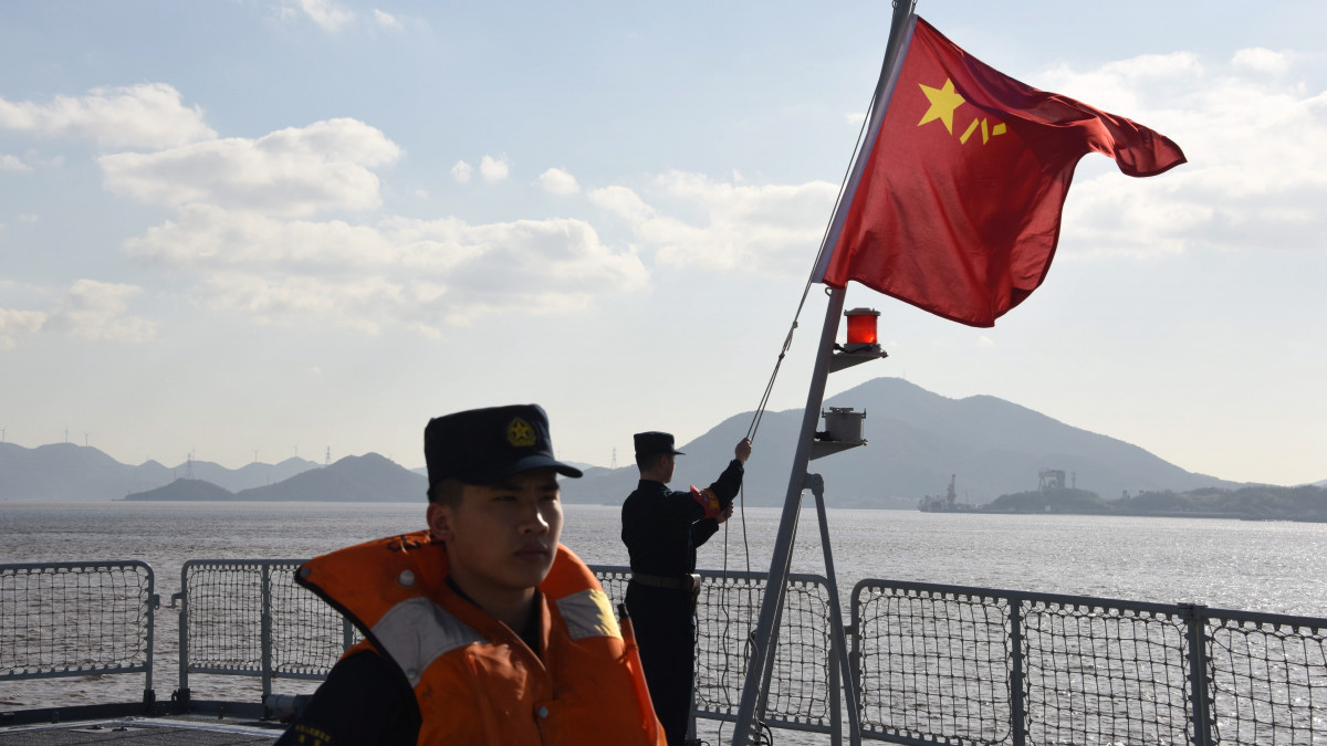 Felvonják a zászlót egy kínai hadihajón a Csöcsiang tartománybeli Csousan hadikikötőjében 2022. december 20-án, a térségben tartandó orosz-kínai hadgyakorlatot megelőző napon. Az egyhetes közös gyakorlatozáson Oroszország a csendes-óceáni flottjának zászlóshajójával, a Varjag rakétacirkálóval, valamint a Saposnyikov marsallról elnevezett fregattal képviselteti magát, míg a kínai haditengerészet egyebek mellett manőverező rakétával felszerelt rombolókat és fregattokat használ a Kelet-kínai-tengeren tarott hadgyakorlaton.