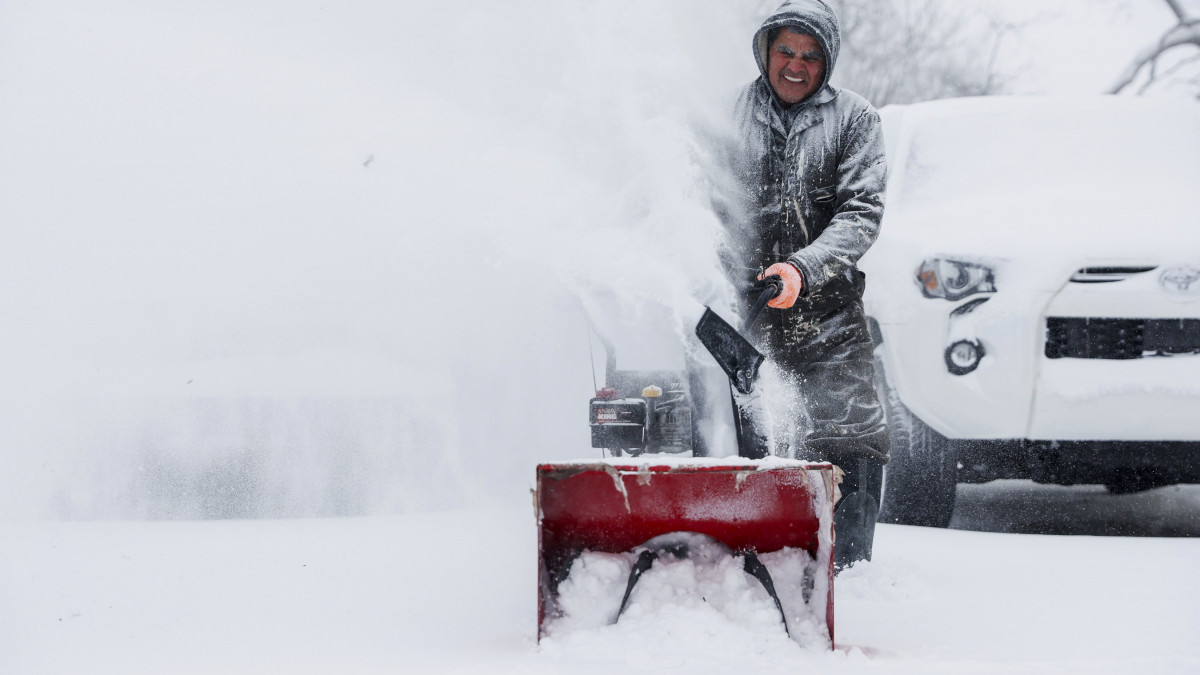 Hófúvóval takarítja a járdát egy férfi a Michigan állambeli Grand Rapids városban 2022. december 23-án. Az Elliott névre keresztelt téli viharzóna miatt az Egyesült Államok területének legnagyobb részén nappal sem emelkedik fagypont fölé a hőmérséklet.
