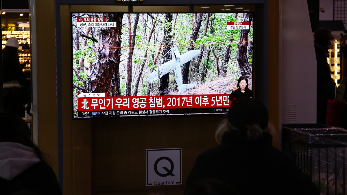 Észak-koreai drónok behatolásáról szóló híradást néző utasok a szöuli főpályaudvaron 2022. december 26-án. A dél-koreai vezérkari főnökök szerint több, pilóta nélküli észak-koreai drón lépte át a Korea-közi határt. Ez az első alkalom 2017 óta, hogy észak-koreai drónok megsértették Dél-Korea légterét. Észak-Korea az előző napokban ballisztikus rakétákat lőtt ki legújabb fegyvertesztjei részeként.