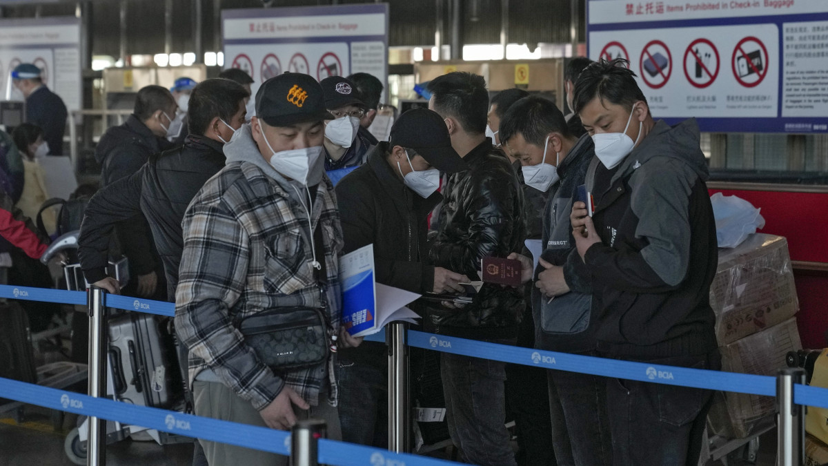 Védőmaszkos utasok a pekingi nemzetközi repülőtéren 2022. december 29-én. A kínai kormány az előző napon jelentette be, hogy a koronavírus-világjárvány miatt több mint két éve bevezetett leállás után ismét elkezdenek új útleveleket kiállítani, ami újra lehetővé teszi a szabad utazást világszerte kínai állampolgároknak. Erre reagálva Japán és az Egyesült Államok kötelező koronavírus-tesztelést ír elő minden Kínából érkező utazóra. Kínában a járványellenes korlátozások december eleji feloldása óta drámaian emelkednek a koronavírusos új esetszámok.