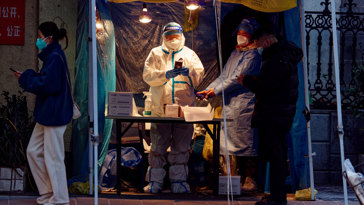 Utcai mintavételi pont koronavírus-vizsgálathoz Sanghajban 2022. december 14-én. A kínai Országos Egészségügyi Bizottság ezentúl nem közli napi jelentésében az új, de tüntementes koronavírus-fertőzöttek számát. December 7-én Kína radikálisan enyhítette a koronavírus-járvány miatt életbe léptetett szigorításokat: megszüntette a kötelező járványtesztelést, és könnyített a karanténszabályokon.