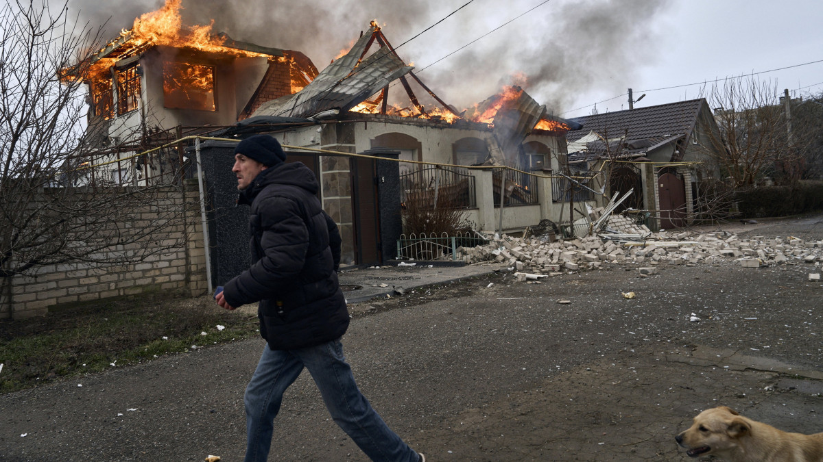 Égő ház mellett egy férfi egy orosz tüzérségi támadás után a dél-ukrajnai Herszonban 2023. január 6-án. Déltől az oroszok egyoldalú tűzszünetet hirdettek az ortodox karácsony alkalmából.