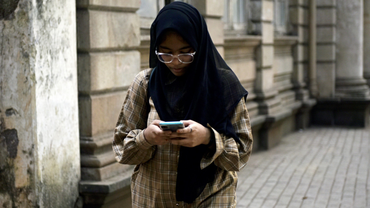 A girl is seeing a mobile phone in Mumbai, India, on December 1, 2022. After two years of pandemic, children are increasingly drawn to the digital world, which is alarming. According to an Indian media report, out of 8,238 responses received from parents with children aged 13 to 17, 71 percent said their children have access to a smartphone for all or most of the day. (Photo by Indranil Aditya/NurPhoto via Getty Images)