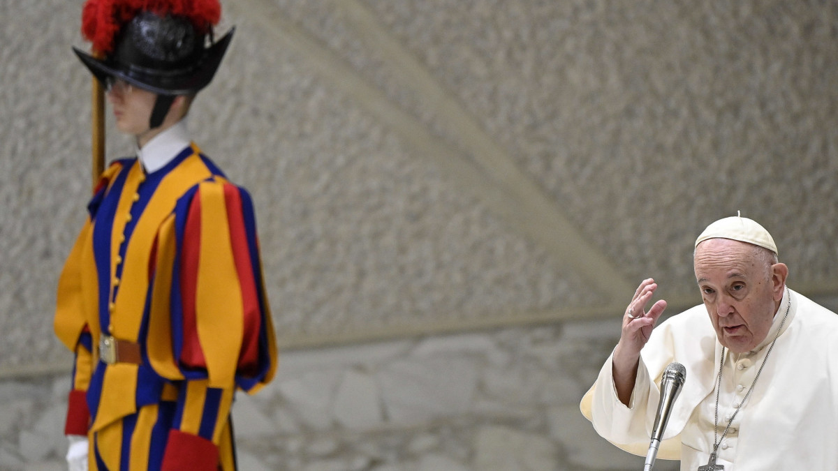 Ferenc pápa egy svájci gárdista mellett heti általános audienciáján a Vatikán VI. Pál pápa termében 2023. január 11-én.