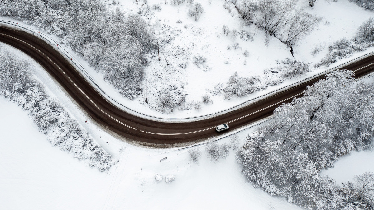 Drónnal készült kép egy behavazott erdőt átszelő útról a délkelet-lengyelországi Krzywcza közelében 2023. január 21-én. A térségben napok óta havazik.