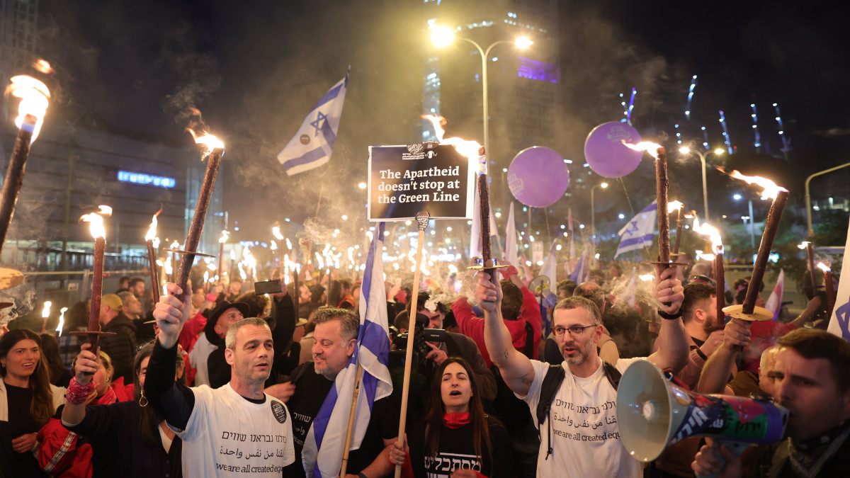 Az új Netanjahu-kormány ellen tüntetnek Tel-Avivban 2023. január 21-én. A rendőrség becslése szerint a városban több mint százezren tüntettek Benjámin Netanjahu miniszterelnök új kormánya ellen. A tiltakozók a jogrendszer átalakításának terve ellen tüntettek, miszerint egyebek között a politikusok felülbírálhatnák a legfelsőbb bíróság végzéseit. Ez a hatalmi ágak eddigi egyensúlyának megbontását, ezzel a demokrácia súlyos sérülését jelentené Izraelben a tiltakozók szerint.