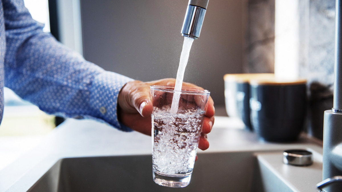 Mature male hand  pouring a glass of water from tap in the kitchen sink