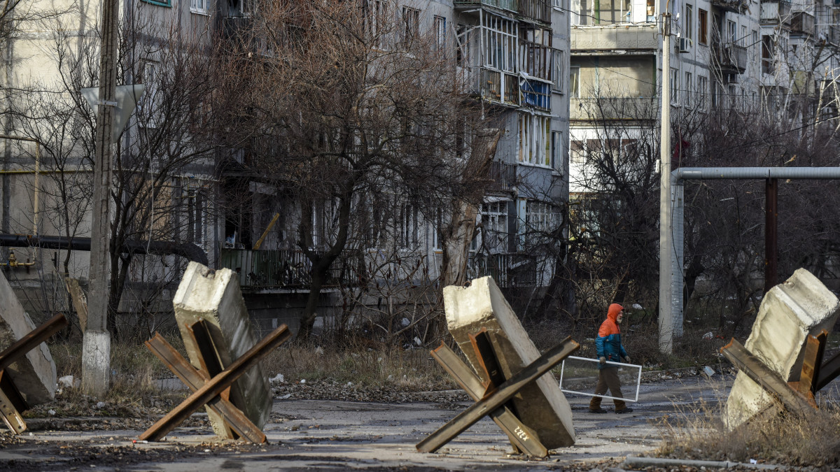 Járókelő megrongált lakóházak előtt, Bahmutban 2023. január 20-án. Az orosz erők ostroma miatt az ukrán hatóságok a kelet-ukrajnai Donyecki területen fekvő város kiürítésére szólították fel a lakosságot, ennek ellenére mintegy nyolcezren az otthonmaradást választották. A városban megszűnt a villany-, a gáz-, a vízszolgáltatás és a távfűtés.