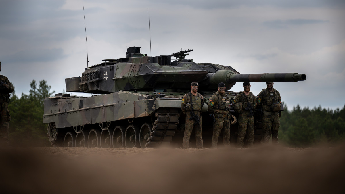 07 June 2022, Lithuania, Pabrade: Soldiers stand in front of a German Army Leopard-2 tank used by the NATO Enhanced Forward Presence Battle Group (eFP battalion) during Chancellor Scholzs visit to Camp Adrian Rohn. Scholz pledged additional military support to Lithuania to defend against a possible Russian attack. Photo: Michael Kappeler/dpa (Photo by Michael Kappeler/picture alliance via Getty Images)