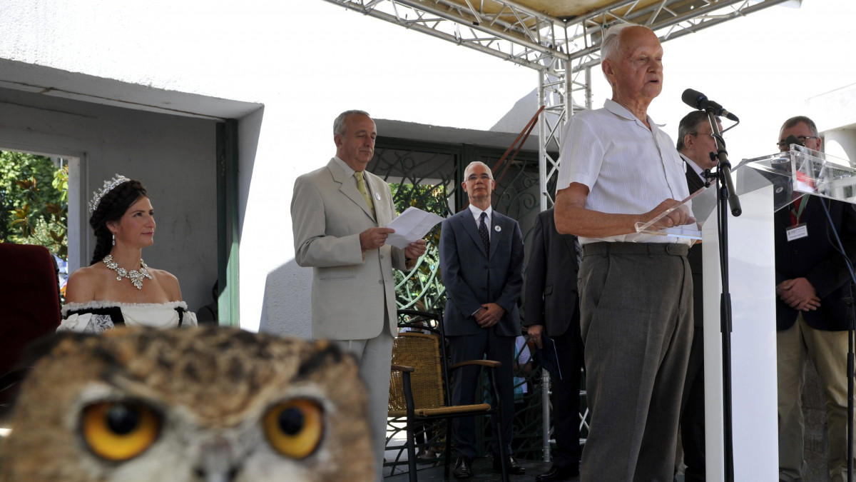 Schmidt Egon ornitológus, Kossuth-díjas író beszédet mond a Fővárosi Állat- és Növénykert megnyitásának 150 éves évfordulója alkalmából rendezett ünnepségen az állatkert főbejáratánál 2016. augusztus 9-én. Mögötte Balog Zoltán, az emberi erőforrások minisztere (b3) és Persányi Miklós, az állatkert főigazgatója, aki miniszteri biztosként felügyeli a Liget-projekt kert- és tájépítészeti beruházásait.