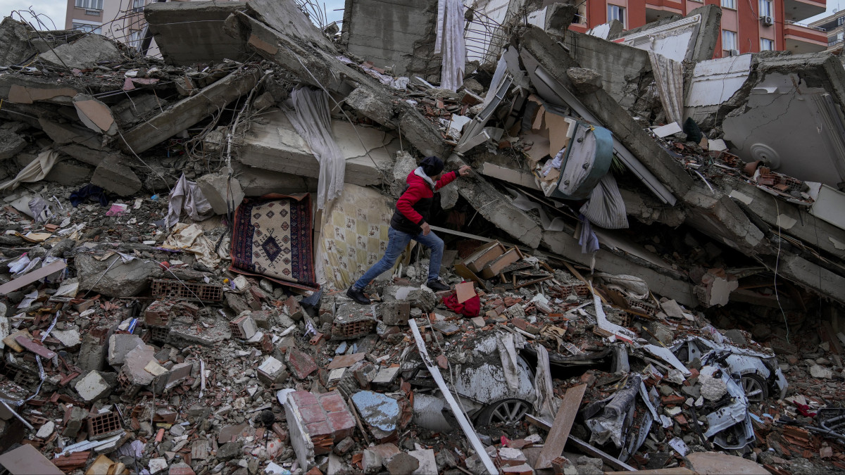 Férfi egy összedőlt épület törmelékhalmán a dél-törökországi Adana nagyvárosban 2023. február 6-án. Hajnalban több erős földrengés rázta meg Törökország délkeleti és Szíria északi részét, a legnagyobb rengés egyes mérések szerint a 7,8-as erősséget is elérte. A földmozgásnak Törökországban és Szíriában is több száz halálos áldozata és több ezer sérüljte van.