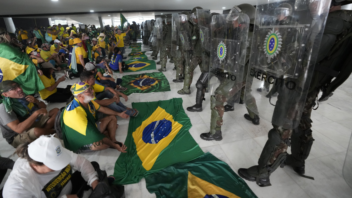 Rohamrendőrök és Jair Bolsonaro korábbi brazil elnök támogatói az épületben, miután a tüntetők megrohamozták és elfoglalták a brazíliavárosi elnöki hivatalt, a Planalto-palotát 2023. január 8-án. A volt elnök támogatói szerint Bolsonaro baloldali ellenfele, Luiz Inácio Lula da Silva csalással győzött a 2022. októberi elnökválasztáson.