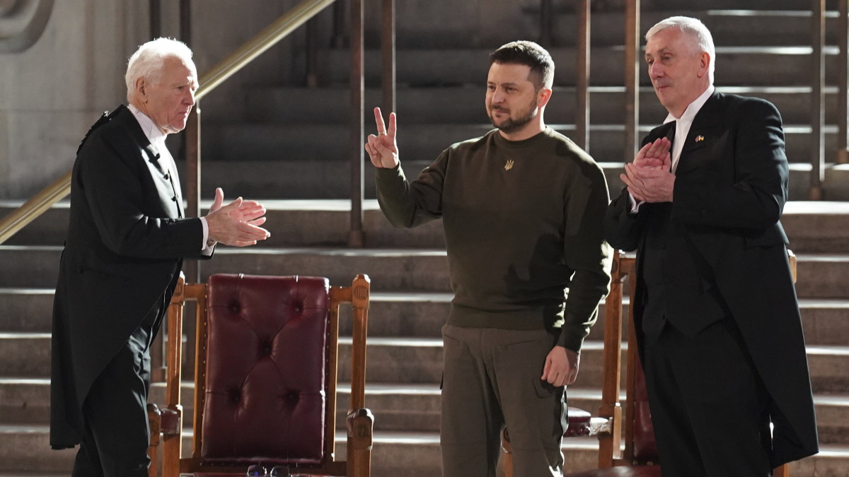 Volodimir Zelenszkij ukrán elnök (k) a béke jelét mutatja a felszólalása után a londoni Westminster-palotában 2023. február 8-án. Balról Lindsay Hoyle, a brit alsóház elnöke, jobbról John McFall, a Lordok Házának elnöke.