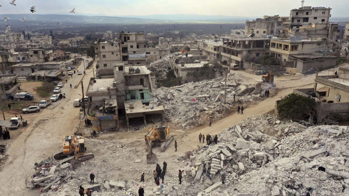 Összedőlt házak romjai között emberek a szíriai Idlíb tartományban fekvő Haremben 2023. február 11-én, öt nappal a Dél-Törökországot és Észak-Szíriát sújtó 7,8-es erősségű földrengés után. A természeti katasztrófa halálos áldozatainak száma meghaladja a 24 ezret, a sérülteké a 85 ezret.