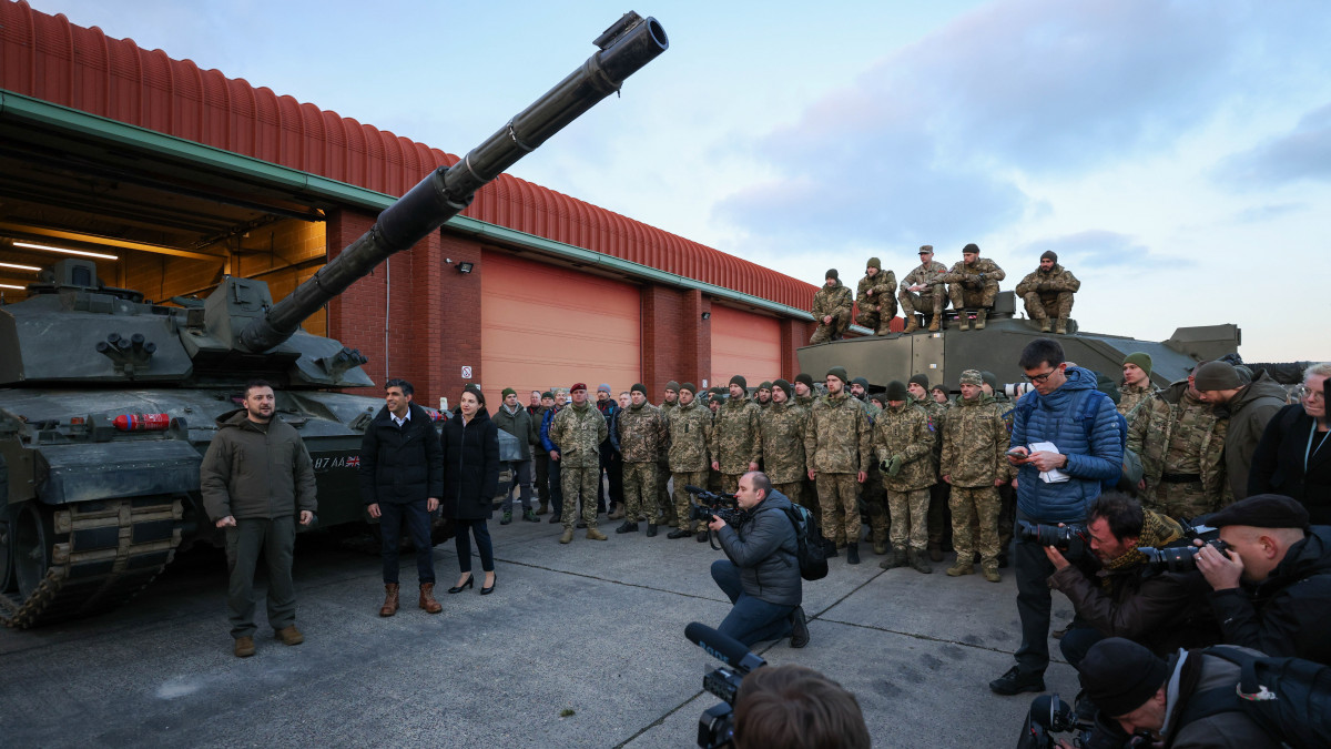 Rishi Sunak brit miniszterelnök (b2) és Volodimir Zelenszkij ukrán elnök (b) egy Challenger 2 páncélozott harckocsi előtt a lulworthi katonai kiképző központban 2023. február 8-án. A brit hadsereg 2022-ben tízezer ukrán katonát képzett ki, 2023-ban a dupláját tervezik.