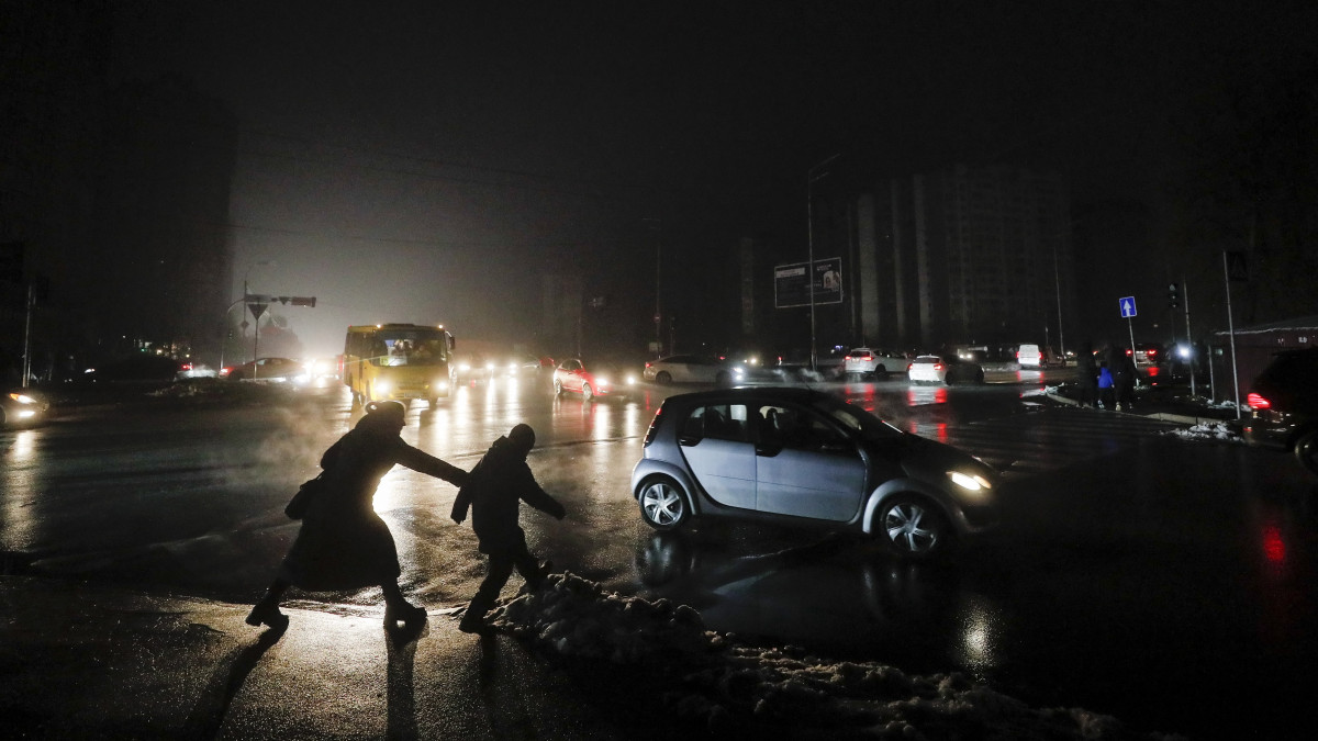 Autók haladnak el közvilágítás nélkül maradt épületek mellett áramszünet idején Kijevben 2022. november 24-én. Az ukrán fővárosban a vízellátás már helyreállt, de a lakóépületek mintegy 70 százaléka áram nélkül maradt az előző napi orosz rakétatámadások után.