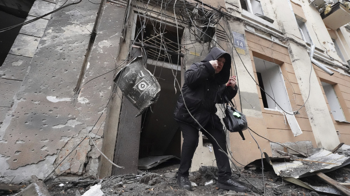 A 2023. február 5-i képen orosz tüzérségi támadástól súlyosan megrongálódott lakóépületből távozik egy nő az északkelet-ukrajnai Harkiv nagyvárosban.