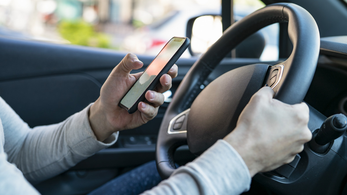 Mid adult manÂ´s hands selecting location on mobile phone while sitting in driverÂ´s seat