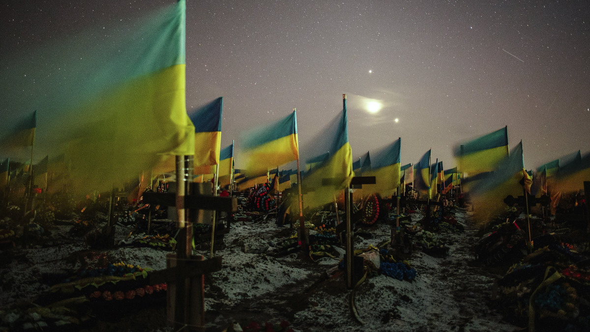 2023. február 23-án közreadott, hosszú expozíciós idővel készített kép ukrán zászlókról a harkivi katonai temetőben február 22-én éjjel. Oroszország 2022. február 24-én indított háborút Ukrajna ellen.