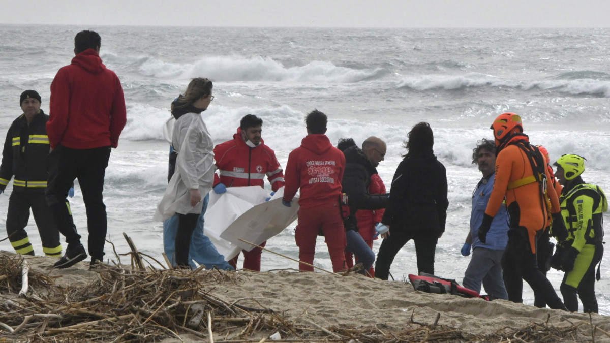 Tűzoltók és az Olasz Vöröskereszt munkatársai dolgoznak a tengerparton, ahol több mint harminc holttestet emeltek ki eddig a vízből a dél-olaszországi Steccato di Cutro közelében 2023. február 26-án. Korábban egy több mint száz fős - Irakból, Pakisztánból és Afganisztánból érkező - csoportot szállító hajó balesetet szenvedett.