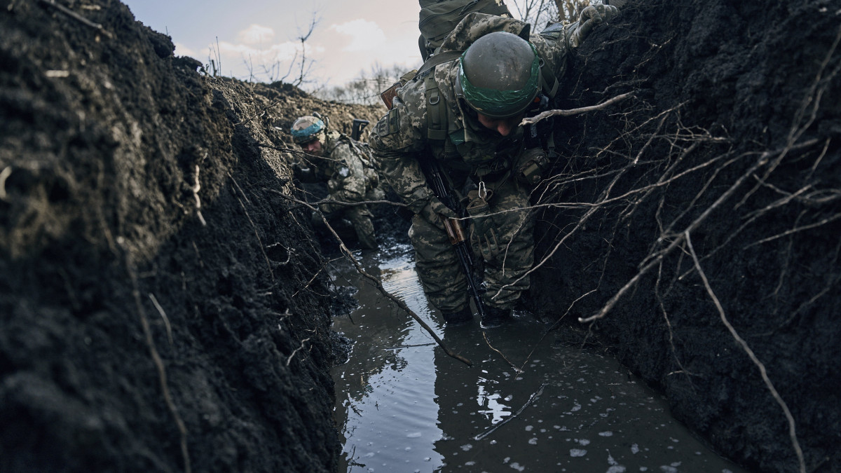 Ukrán katonák egy vízben álló lövészárokban gázolnak a donyecki régióban fekvő, ostromgyűrűben lévő Bahmutban 2023. március 5-én. Bahmutot az ukrán védelmi erők tartják ellenőrzésük alatt, míg az orosz egységek erőiket a környező települések irányában történő támadó műveletek végrehajtására összpontosítják.