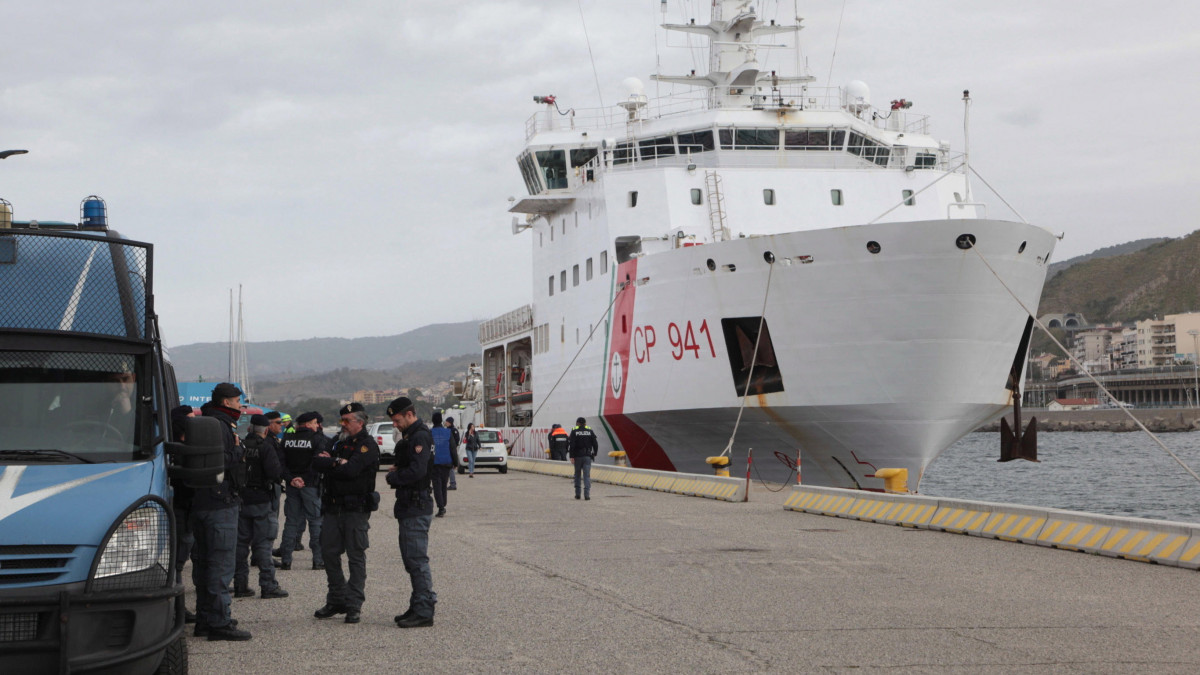 Az olasz parti őrség Diciotti hajója mellett rendőrök a dél-olaszországi Reggio Calabria kikötőjében 2023. március 11-én, miután a hajó kimentett 584, Európába igyekvő illegális bevándorlót a viharos tengerből.