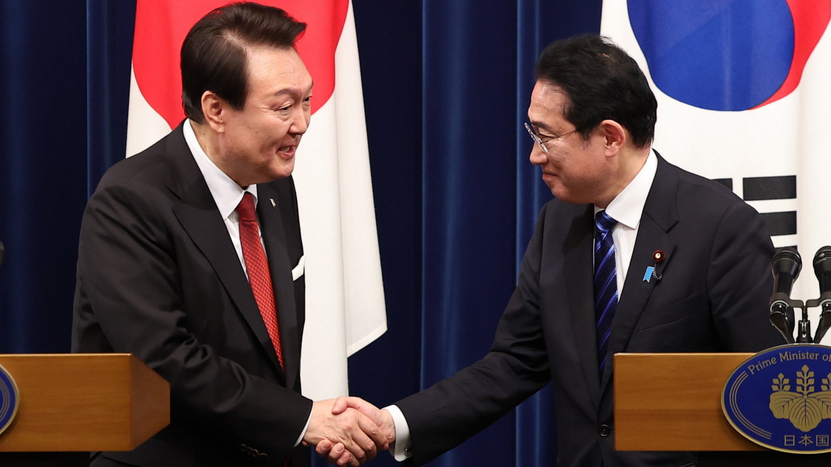 Jun Szok Jol dél-koreai elnök (b) és Kisida Fumio japán kormányfő kezet fog a tokiói miniszterelnöki hivatalban tartott sajtótájékoztatójuk végén 2023. március 16-án. A csúcstalálkozó 12 év óta az első a két szomszédos hatalom között.