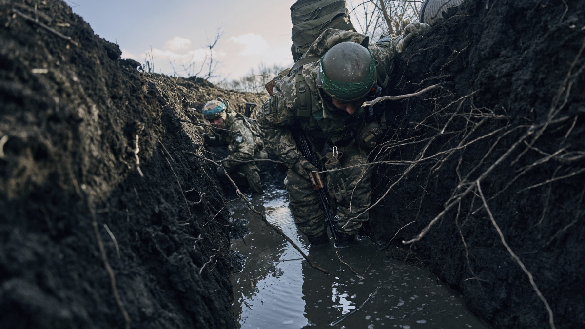Ukrán katonák egy vízben álló lövészárokban gázolnak a donyecki régióban fekvő, ostromgyűrűben lévő Bahmutban 2023. március 5-én. Bahmutot az ukrán védelmi erők tartják ellenőrzésük alatt, míg az orosz egységek erőiket a környező települések irányában történő támadó műveletek végrehajtására összpontosítják.
