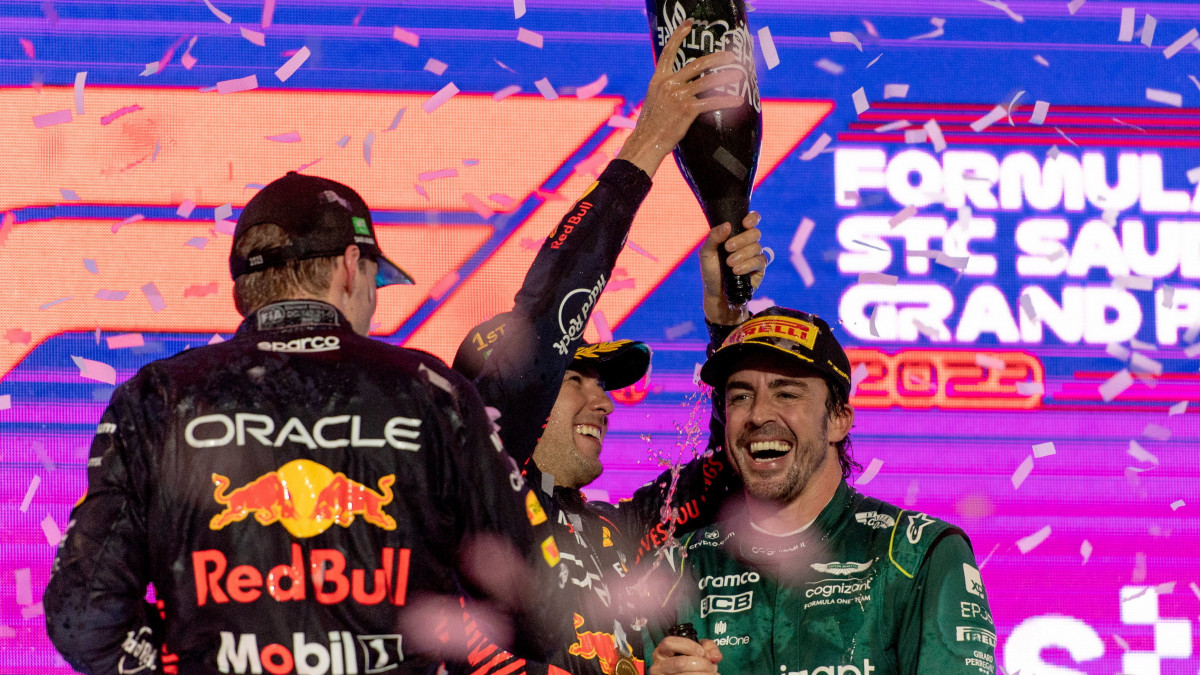A győztes Sergio Pérez, a Red Bull mexikói versenyzője (k), második helyezett holland csapattársa, Max Verstappen (b) és a harmadik helyezett Fernando Alonso, az Aston Martin spanyol versenyzője pezsgővel ünnepel a Forma-1-es autós gyorsasági világbajnokság Szaúdi Nagydíjának eredményhirdetésén a dzsiddai utcai versenypályán 2023. március 19-én.