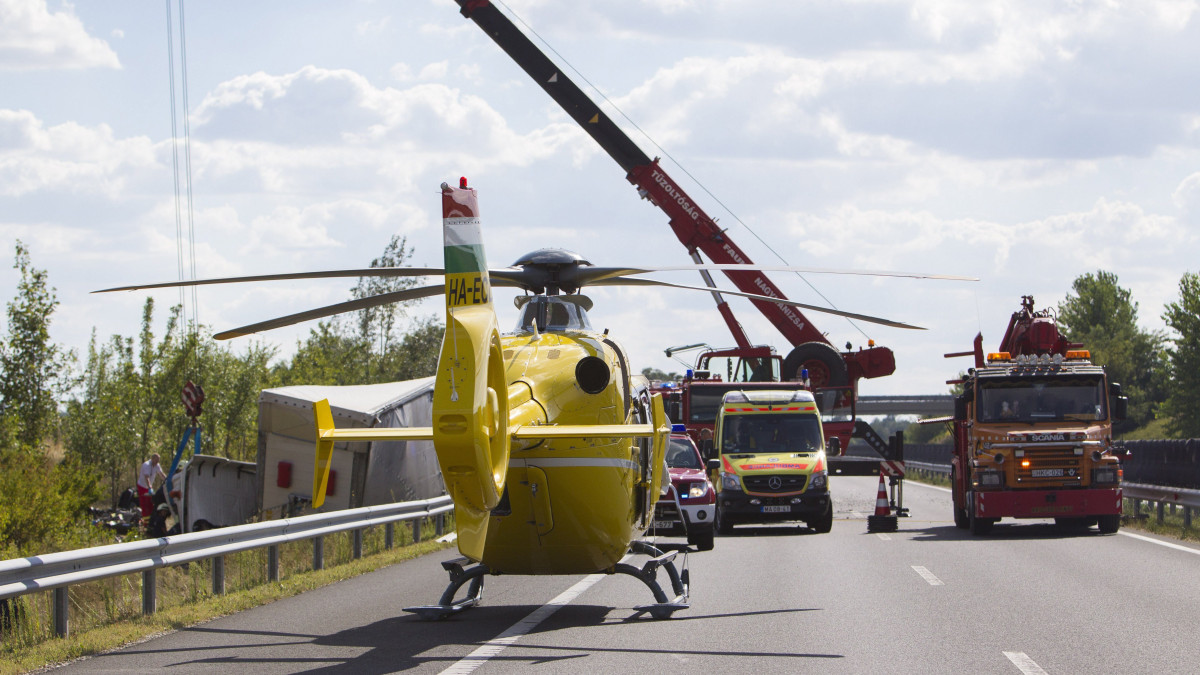 Mentőhelikopter várakozik egy felborult pótkocsis kamion sérült sofőrje kiszabadításánál  az M7-es autópálya Budapest felé vezető oldalán, Galamboknál 2017. augusztus 14-én. A kamion előzőleg szalagkorlátnak ütközött, majd felborult.