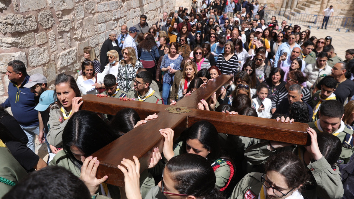 Keresztény hívők fakeresztet visznek, amint végigjárják Jézus Krisztus keresztútját a Szent Sír-bazilikához vezető Via Dolorosán, a jeruzsálemi Óvárosban nagypénteken, 2023. április 7-én.