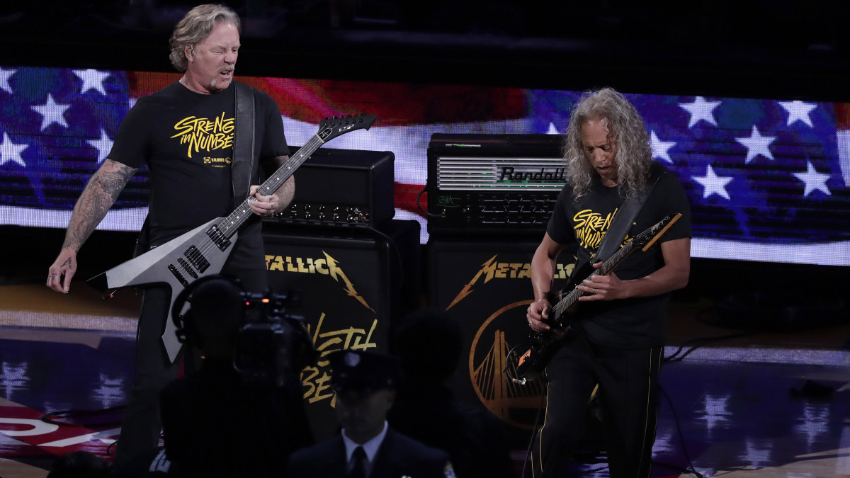 James Hetfield, a Metallica amerikai metálzenekar énekese (b) Kirk Hammet szólógitárossal, amint az együttes előadja az ország himnuszát az észak-amerikai kosárlabda-liga döntőjében játszandó Toronto Raptors - Golden State Warriors mérkőzés előtt a kaliforniai Oakland Oracle Arénájában 2019. június 5-én.