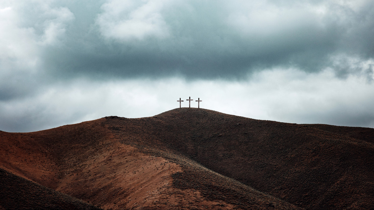 A depiction of the Easter story, three crucifixes line the top of a barren gloomy hill.  A crucial point in Christian history.