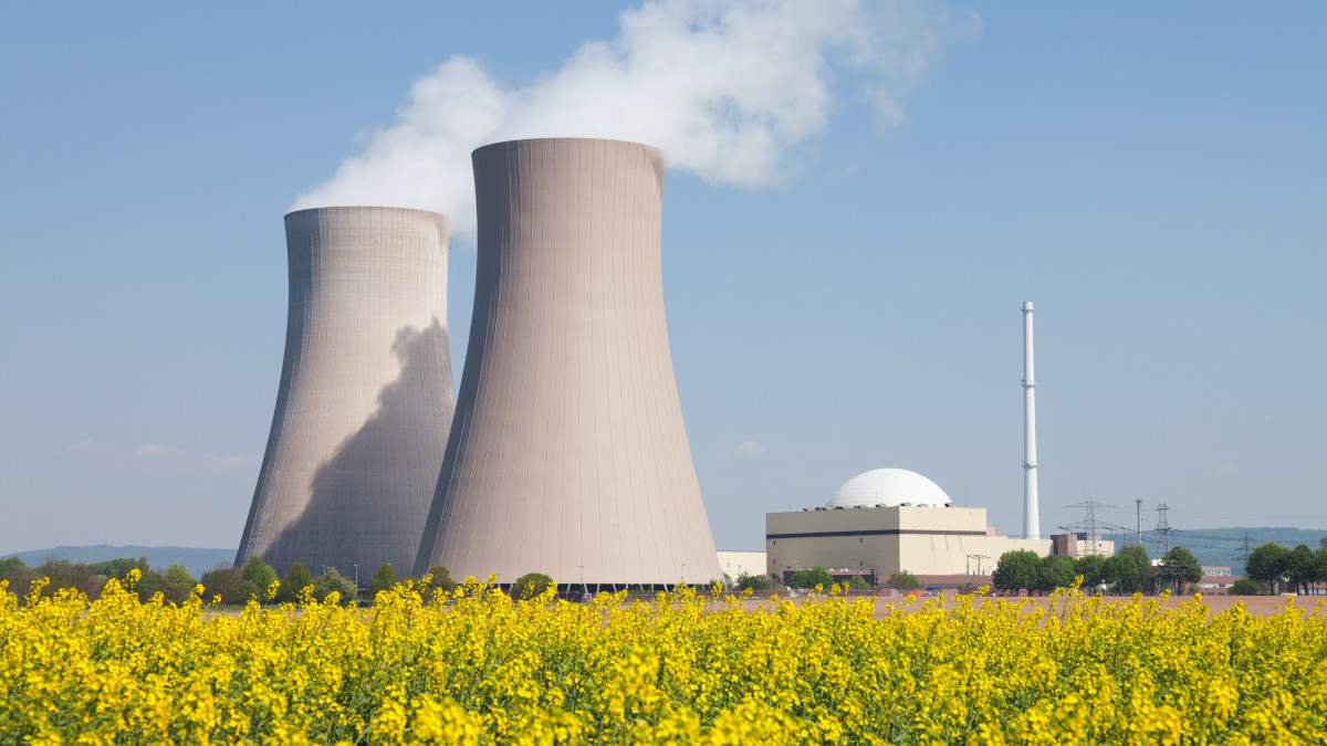 Nuclear power station with steaming cooling towers and blooming canola field. Location: Lower Saxony, Germany.