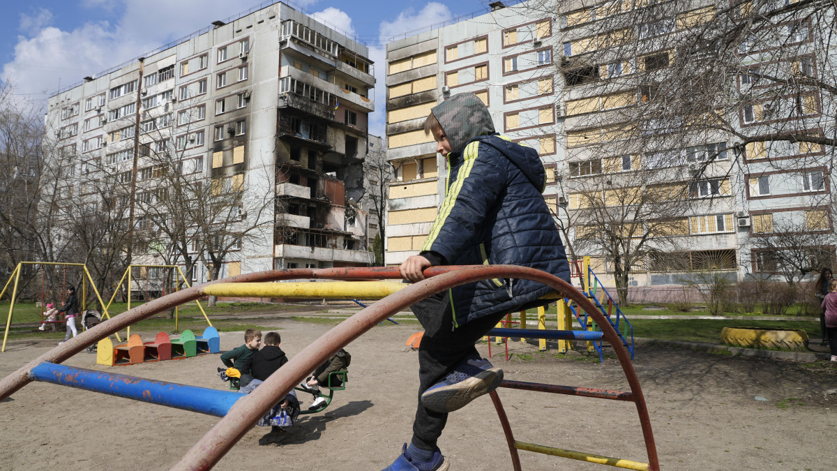 Gyerekek egy játszótéren egy orosz rakétatámadásban súlyosan megrongálódott lakóház előtt a délkelet-ukrajnai Zaporizzsjában 2023. március 27-én.