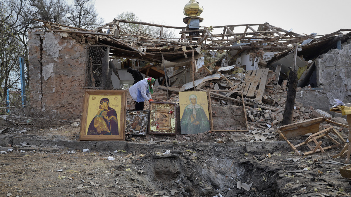 Ukrán asszony szentképeket és kegytárgyakat ment ki a megsemmisült helyi ortodox templom romjai közül egy orosz rakétatámadás után a délkelet-ukrajnai Zaporizzsjai területen fekvő Komisuvahában 2023. április 16-án, az ortodox húsvét napján.