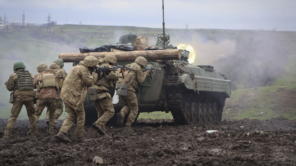 Ukrán katonák páncélozott harcjárművük fedezékében a kelet-ukrajnai Donyecki területen húzódó front térségében tartott gyakorlaton 2023. április 15-én, az Ukrajna elleni orosz háború alatt.