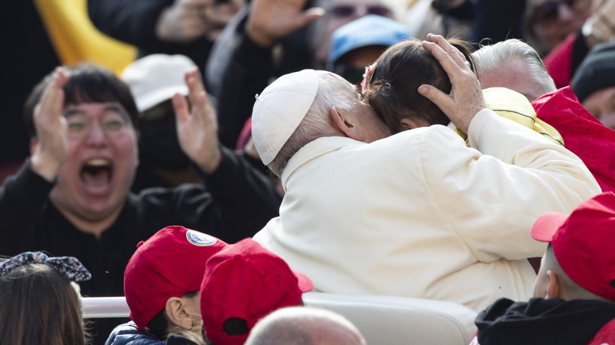Ferenc pápa megpuszil egy gyermeket hetenkénti általános kihallgatásán a vatikáni Szent Péter téren 2023. április 19-én.