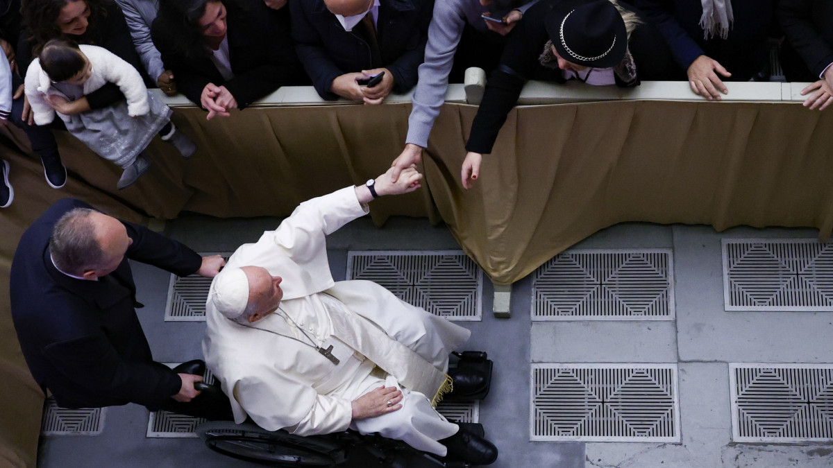 Ferenc pápa kerekesszékben érkezik a Vatikán közel háromezer egyházi és világi dolgozójának képviselőivel tartandó karácsonyi összejövetelre a pápai állam VI. Pál pápa termében 2022. december 22-én.