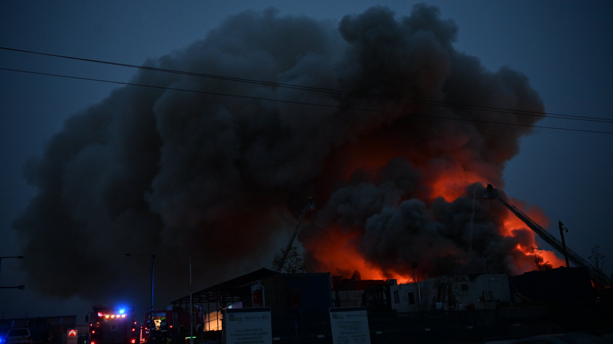 Létráról oltják a lángokat tűzoltók a XXIII. kerületben, ahol tűz ütött ki egy autóbontóban 2023. április 28-án.