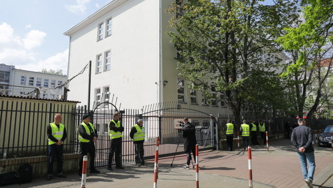 A varsói polgármesteri hivatal biztonsági személyzetének tagjai őrt állnak az orosz gimnázium épületének bejárata előtt Varsóban 2023. április 29-én. Lengyelország lefoglalta az épületet, miután a varsói polgármesteri hivatal beadványára meghozott bírósági határozat szerint az ingatlan a lengyel állam tulajdona. Oroszország azonnal tiltakozott a lépés miatt, és ígérete szerint hivatalos diplomáciai tiltakozást is át fog adni.