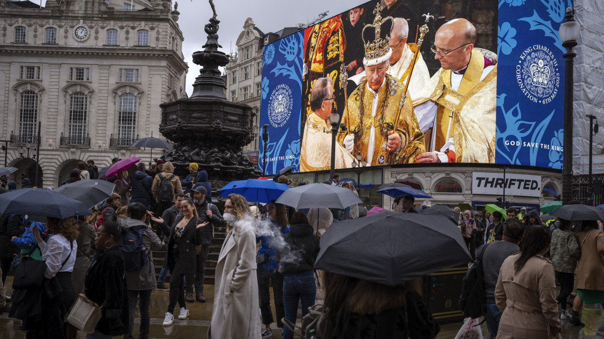 III. Károly brit királynak a Westminster-apátságban tartott koronázási ünnepségét mutató óriáskivetítő előtt járókelők a londoni Piccadilly Circusön 2023. május 6-án.