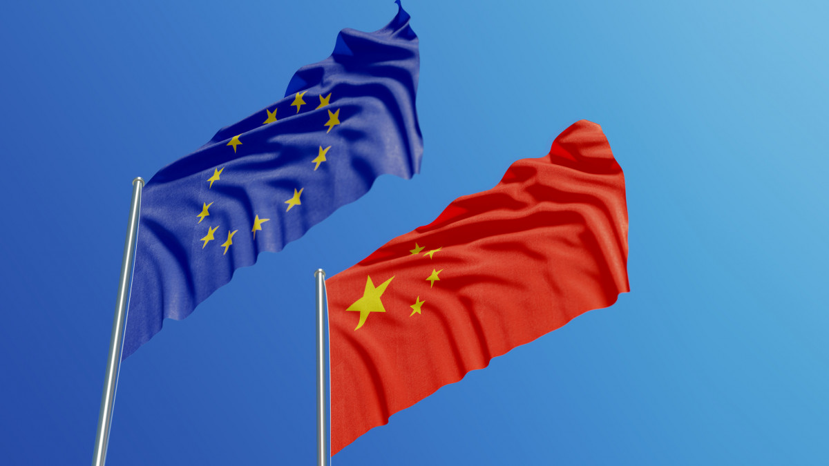 European Union and Chinese flags are waving with wind over blue sky. Low angle view. Dispute and conflict concept. Horizontal composition with copy space.