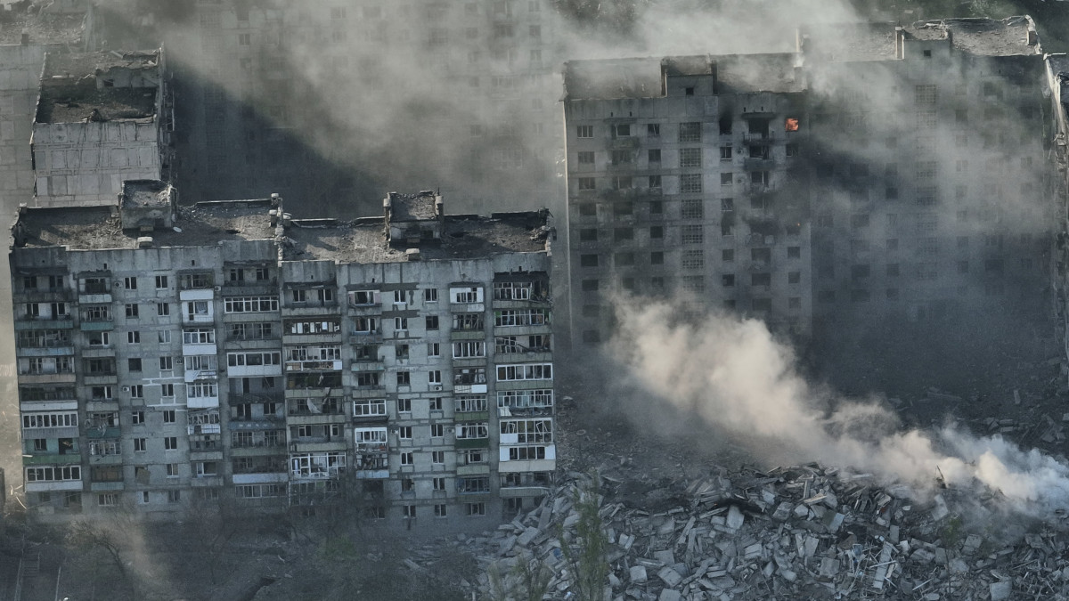 Találatot kapott épületek füstölnek az orosz erők által ostromlott kelet-ukrajnai Bahmutban 2023. április 26-án.